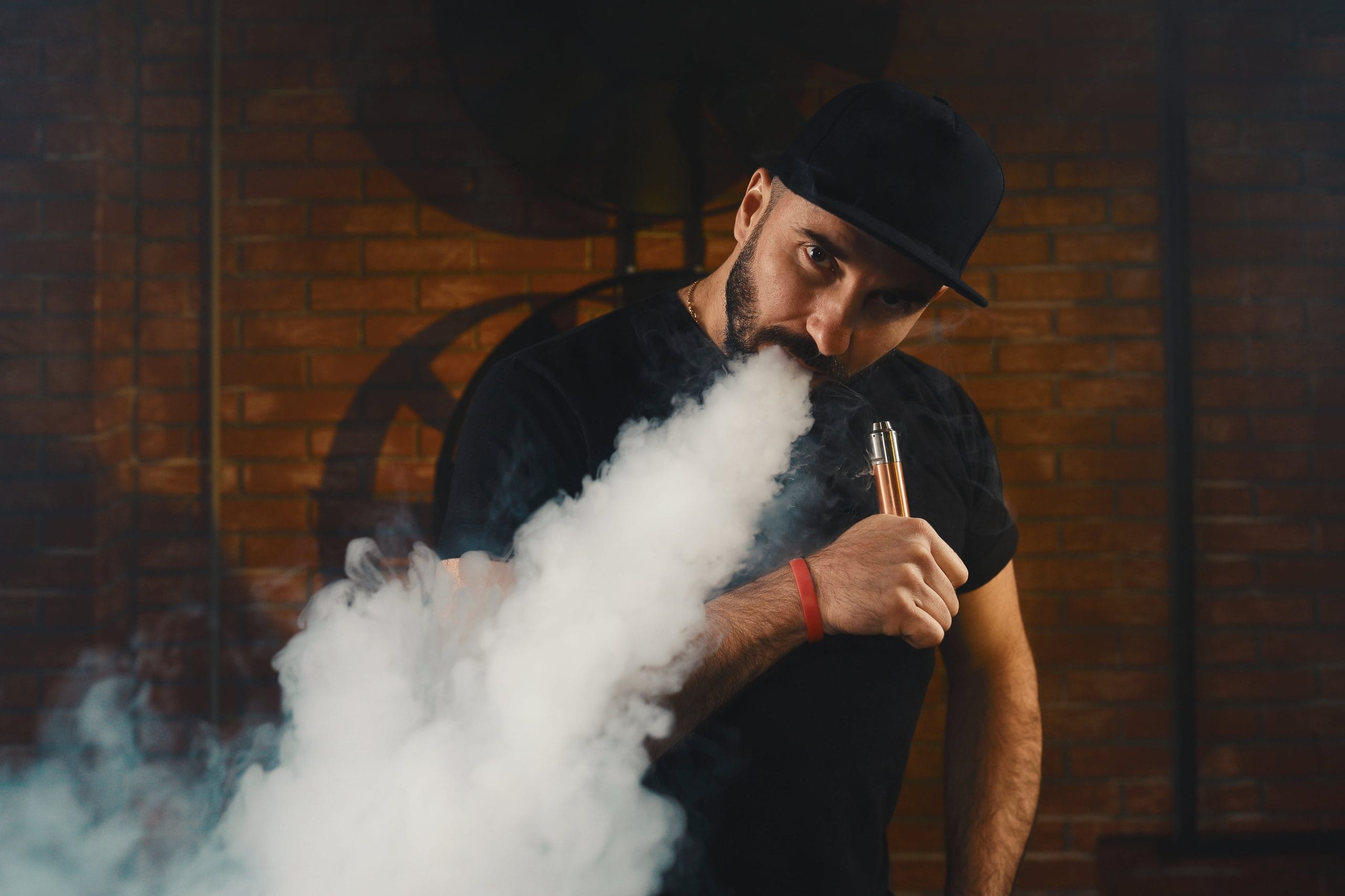 Man vaping an electronic cigarette at a vape shop in Arlington, TX, exhaling thick vapor in a stylish indoor setting.